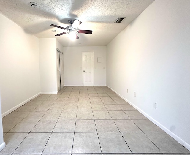 tiled empty room featuring ceiling fan and a textured ceiling