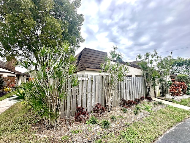 view of side of property with mansard roof and fence