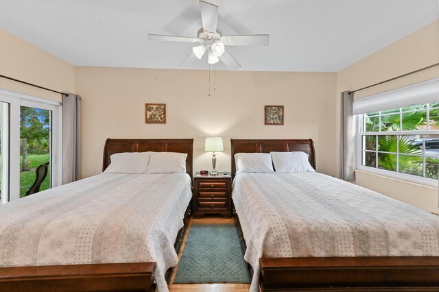 bedroom with ceiling fan, wood-type flooring, and stainless steel fridge