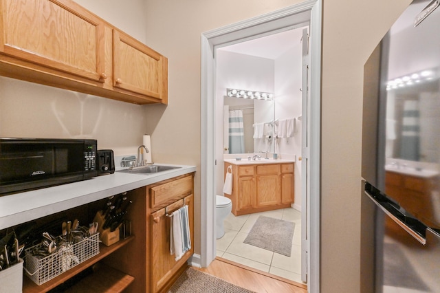 kitchen with light tile patterned floors, light brown cabinetry, and sink