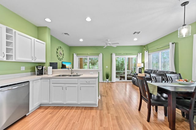 kitchen featuring decorative light fixtures, light wood-type flooring, stainless steel dishwasher, white cabinets, and sink