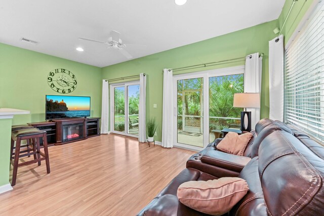 living room with light wood-type flooring, ceiling fan, and a wealth of natural light