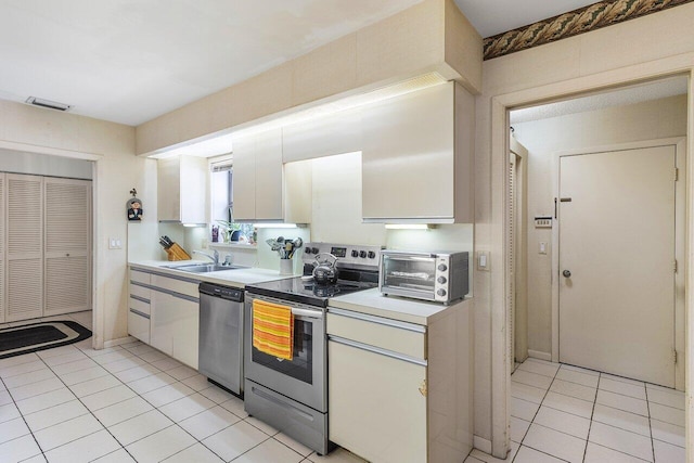 kitchen with white cabinets, light tile patterned floors, sink, and appliances with stainless steel finishes