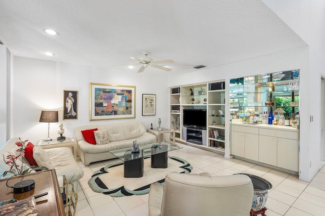 living room with ceiling fan, light tile patterned floors, and a textured ceiling