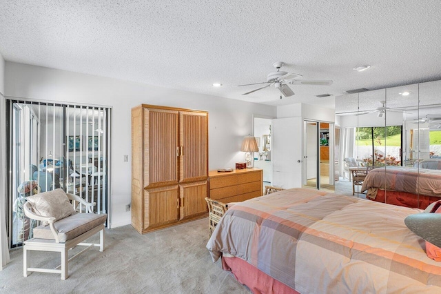 bedroom featuring a textured ceiling, light colored carpet, and ceiling fan