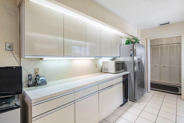 kitchen featuring white cabinets, light tile patterned flooring, and stainless steel refrigerator with ice dispenser