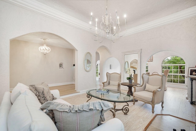 living area with a chandelier, arched walkways, light wood-style flooring, baseboards, and ornamental molding