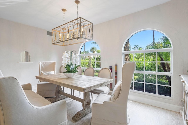 dining area featuring baseboards, light wood finished floors, visible vents, and a notable chandelier