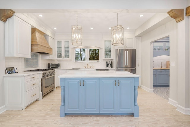 kitchen featuring custom range hood, a center island, hanging light fixtures, stainless steel appliances, and light countertops