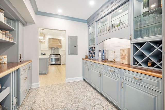 bar featuring stainless steel stove, premium range hood, a sink, electric panel, and crown molding