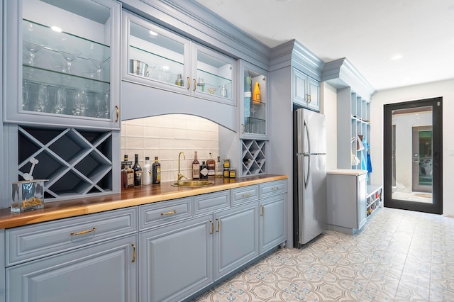 bar featuring a bar, a sink, freestanding refrigerator, and decorative backsplash