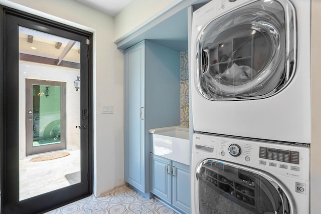 washroom featuring a sink, stacked washer and dryer, light tile patterned floors, and cabinet space