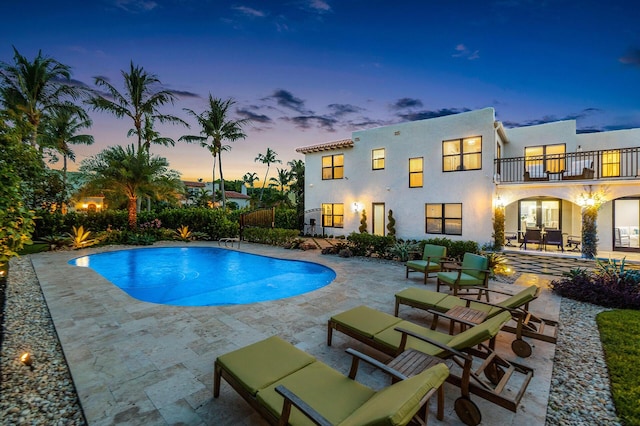 pool at dusk featuring an outdoor pool and a patio