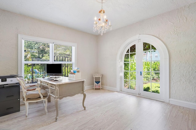 office space with light wood-style flooring, baseboards, a notable chandelier, and a textured wall