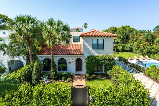 mediterranean / spanish house featuring a front yard, a tiled roof, and stucco siding