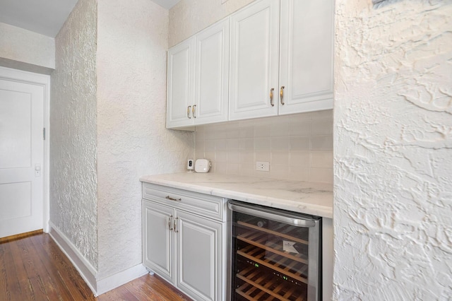 bar with a textured wall, wine cooler, baseboards, tasteful backsplash, and dark wood finished floors