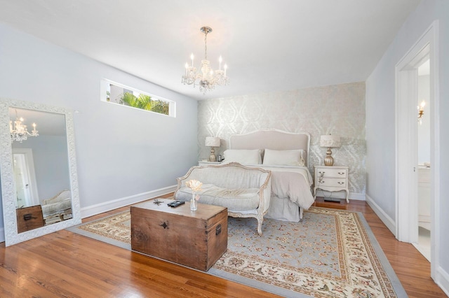 bedroom with wallpapered walls, baseboards, an accent wall, wood finished floors, and a notable chandelier