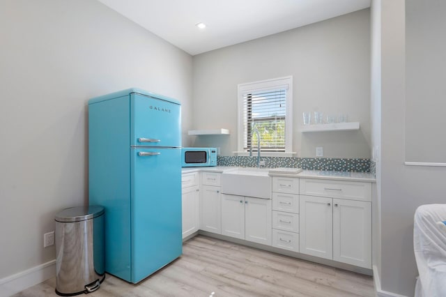 kitchen featuring refrigerator, open shelves, light countertops, white cabinets, and a sink