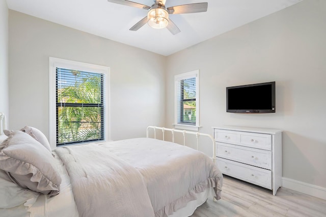 bedroom with light wood finished floors, baseboards, and a ceiling fan