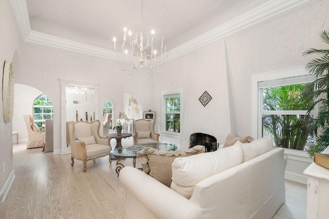 living area with arched walkways, a large fireplace, and ornamental molding