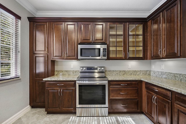 kitchen with dark brown cabinetry, light stone countertops, crown molding, light tile patterned flooring, and appliances with stainless steel finishes