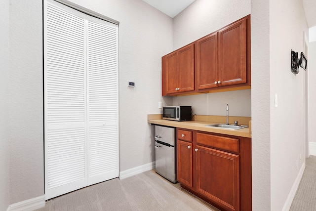 kitchen featuring stainless steel appliances, light colored carpet, and sink