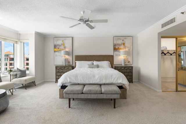 bedroom featuring a textured ceiling, light colored carpet, ceiling fan, and crown molding