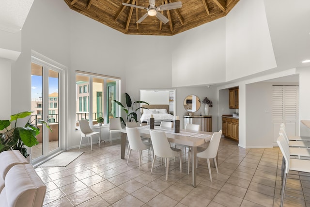 tiled dining room with a high ceiling, ceiling fan, wooden ceiling, and beam ceiling