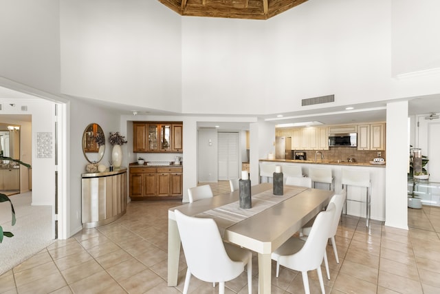 dining room featuring a towering ceiling and light tile patterned floors