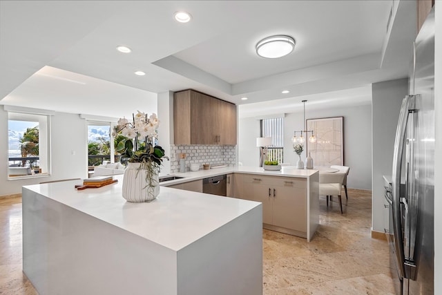 kitchen with pendant lighting, backsplash, a tray ceiling, kitchen peninsula, and stainless steel appliances