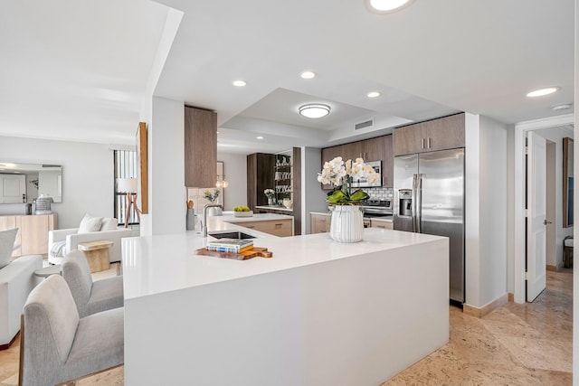 kitchen featuring kitchen peninsula, stainless steel fridge, a tray ceiling, and sink