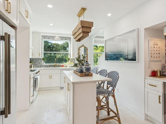 kitchen with white cabinetry, stainless steel stove, a center island, and a breakfast bar