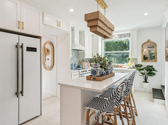 kitchen with a center island, white cabinets, white appliances, wall chimney range hood, and backsplash