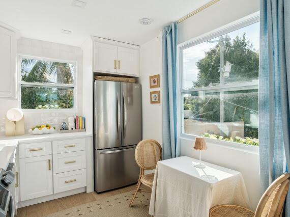 kitchen with stainless steel fridge, light wood-type flooring, and white cabinets