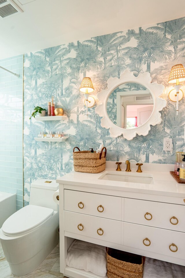 full bathroom with tiled shower / bath, vanity, and toilet