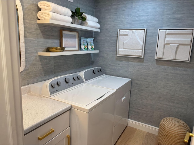 clothes washing area with hardwood / wood-style flooring, independent washer and dryer, and cabinets