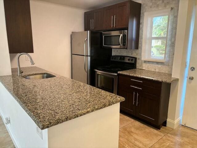 kitchen featuring light stone countertops, sink, kitchen peninsula, light tile patterned floors, and appliances with stainless steel finishes