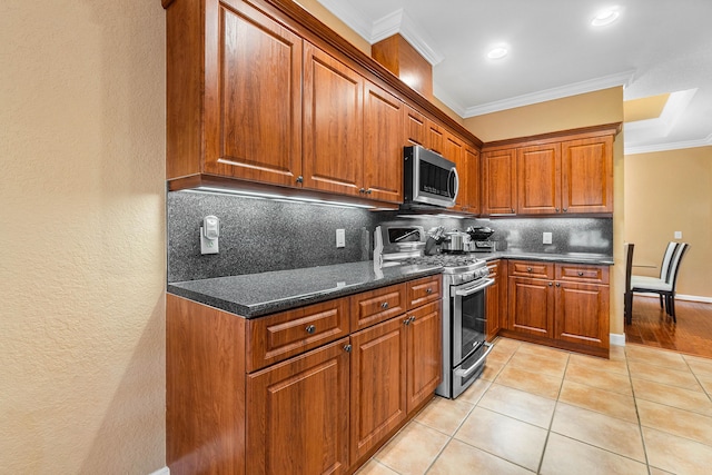 kitchen with decorative backsplash, ornamental molding, stainless steel appliances, and light tile patterned floors