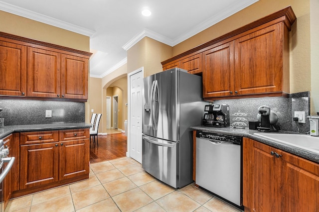 kitchen with tasteful backsplash, light tile patterned flooring, stainless steel appliances, and ornamental molding