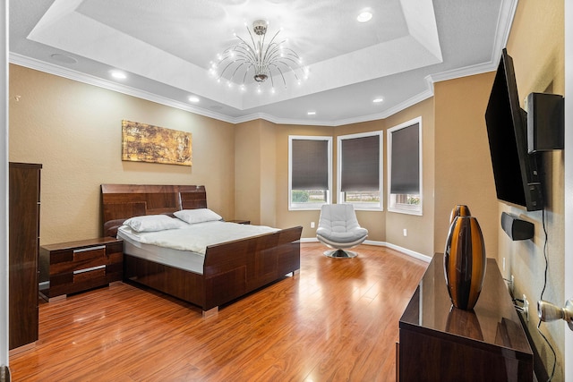 bedroom featuring a raised ceiling, an inviting chandelier, ornamental molding, and light wood-type flooring