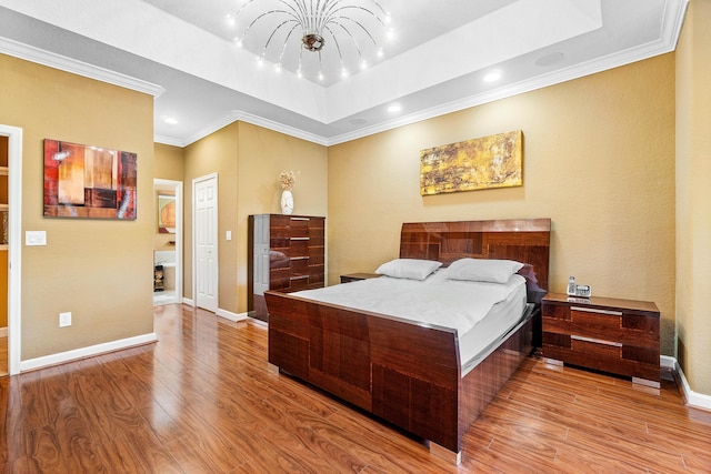 bedroom featuring a notable chandelier, a raised ceiling, crown molding, and light hardwood / wood-style flooring