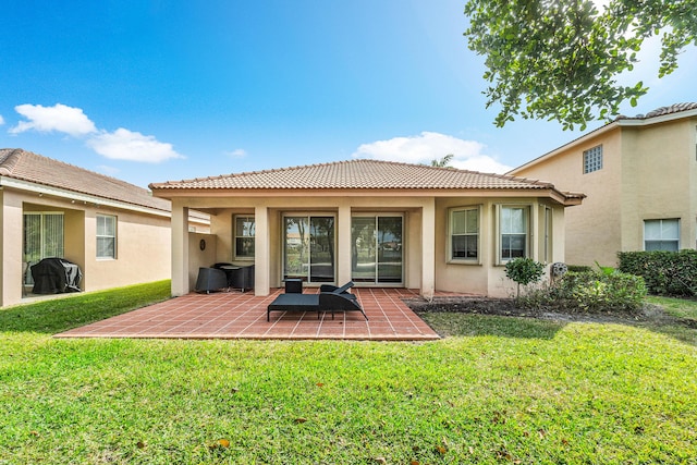 rear view of property featuring a lawn and a patio area