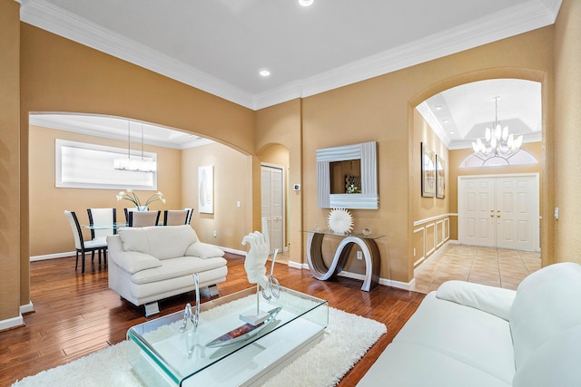 living room with wood-type flooring, crown molding, and a chandelier