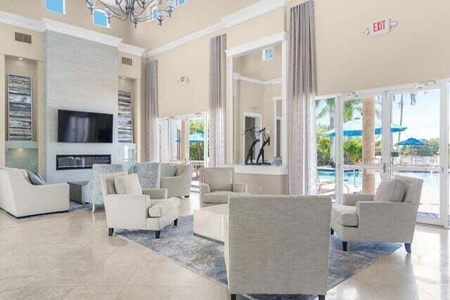 living room featuring a wealth of natural light, crown molding, a large fireplace, and a high ceiling