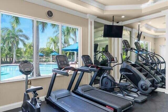 exercise room with a tray ceiling and ornamental molding