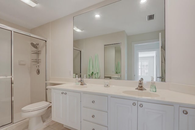 bathroom featuring tile patterned flooring, vanity, toilet, and a shower with shower door