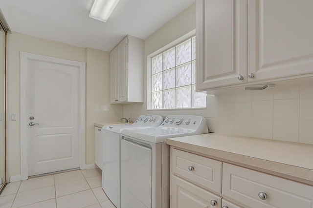 clothes washing area featuring cabinets, light tile patterned floors, and washing machine and dryer