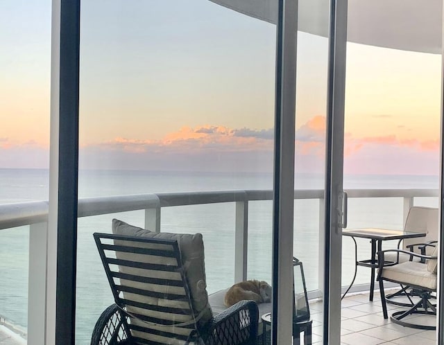 balcony at dusk featuring a water view