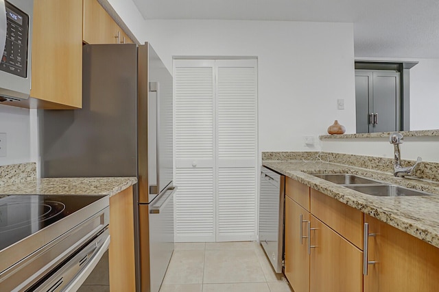 kitchen featuring light tile patterned flooring, stainless steel appliances, light stone countertops, and sink