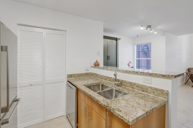 kitchen featuring light stone countertops, dishwasher, sink, kitchen peninsula, and light tile patterned floors